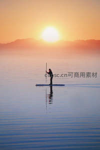 日落时分单人桨板划过如镜湖面