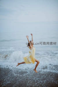 黄裙女子海边跳跃溅起浪花瞬间