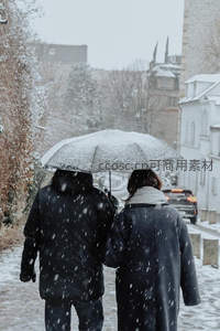 雪中情侣共撑伞漫步城市街巷