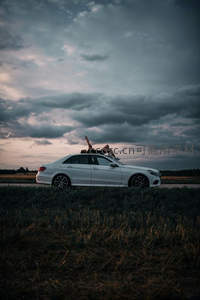 暮色田野中，白车顶上的人影与云霞共舞