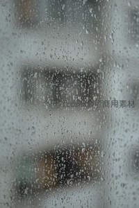 雨滴滑落玻璃窗的朦胧城市背景