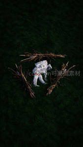 宇航员在深绿草地上与枯枝共舞