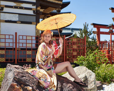 金伞和服女坐岩石前古建筑