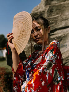 红衣和服女子执扇遮面显神秘