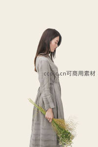 低头持花的优雅女子，简约背景衬托宁静之美