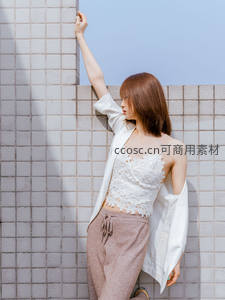 白衫女子倚墙享受阳光