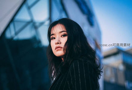 都市背景下深色条纹外套女子凝视
