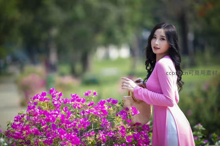 粉衣女子花园赏花侧影