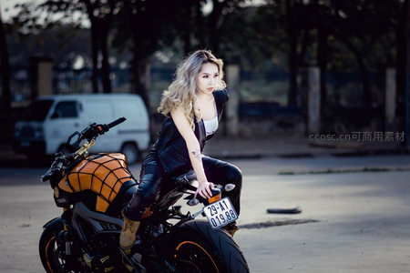 金发女骑手坐于橙黑机车之上