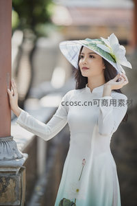 白衣女子倚柱凝望，头戴莲花帽