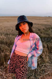 田野中的时尚少女，戴着渔夫帽凝视镜头