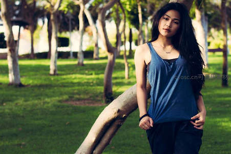 树影斑驳下，长发女孩倚靠枝干静谧凝望