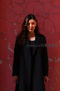 红墙裂纹前黑衣女子沉静伫立