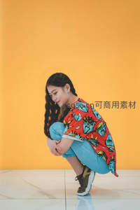 橙色背景下女孩蹲姿俏皮可爱
