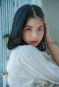 蓝墙旁沉思短发女子