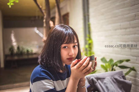 庭院中少女手持茶杯凝视镜头