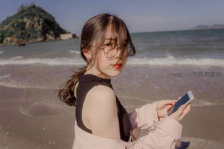 海滩少女戴眼镜，手持手机望远方