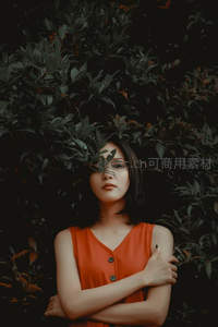 红衣女子隐于绿叶光影间