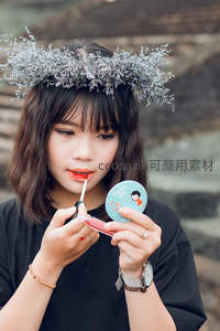 头戴花环女子对镜涂口红