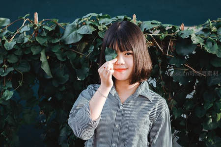 用绿叶遮眼的俏皮女孩