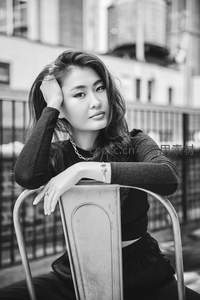 黑白光影下的沉思女子，倚椅凝神