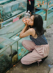 女子轻吻袋中金鱼，水族市场温馨一刻