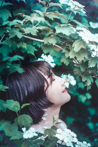 少女仰望花丛，绿意盎然中静享自然
