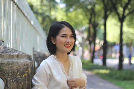 白衣女子倚墙微笑，林荫小道春意盎然