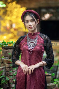 红衣女子身着传统奥黛立于庭院