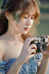 少女手持复古相机，面颊点缀绿叶，温柔凝视镜头