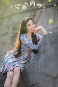 蓝裙少女倚石微笑，樱花枝头绽放，春意盎然