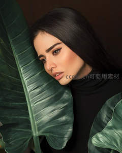 黑发女子倚靠绿叶静谧写真