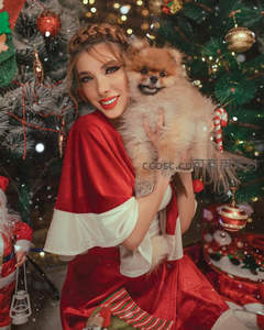 圣诞树前抱着博美犬的微笑女子