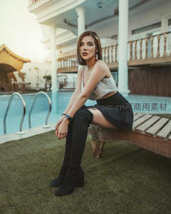 泳池边长靴美女坐木凳，度假风造型吸睛