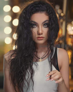 深色卷发美女在暖光下眼神迷离特写