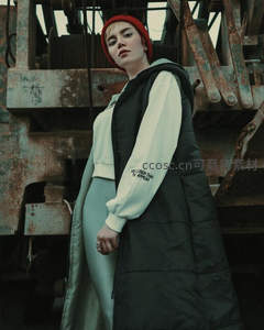 红帽青年立于锈蚀机械前凝视镜头