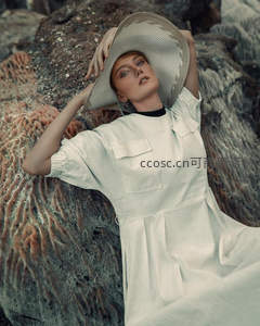 岩石旁的优雅女士，宽檐帽与素色连衣裙