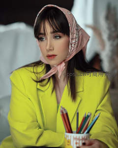 黄衣女子手持彩笔杯目光沉静