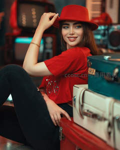 红帽女孩微笑轻扶帽檐倚行李箱