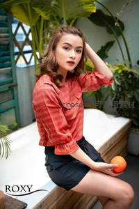 红格衬衫女手持橙子坐庭院