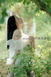 阳光穿透绿叶，白衣女子闭目享受自然