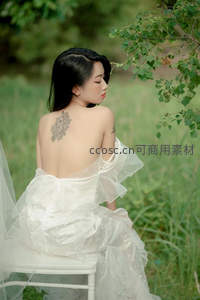 背影纹身女子静坐草地白椅