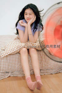 风扇旁微笑少女，格纹床单映衬温柔时光