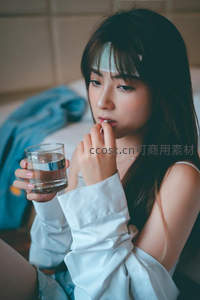 病中女子服药喝水，神情专注