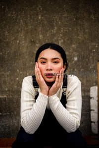 素颜少女托腮凝视，质朴背景衬托纯真表情