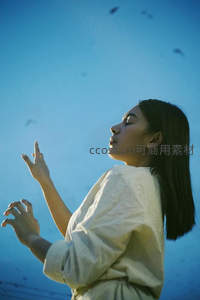 女子仰望蓝天双手轻扬如祈祷