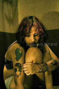 纹身少女蜷坐角落神情忧郁