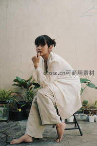 庭院中沉思的女子，简约白袍与绿植相伴