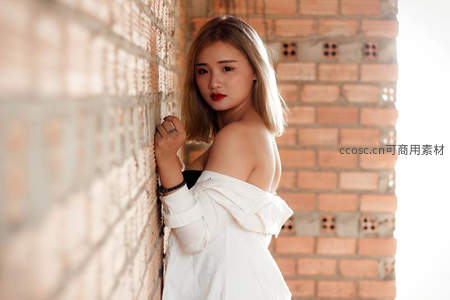 砖墙边白裙少女回眸，阳光洒落肩头