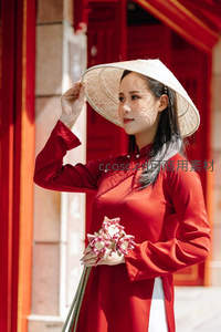 红衣斗笠女轻扶帽檐，手持莲花笑靥如花